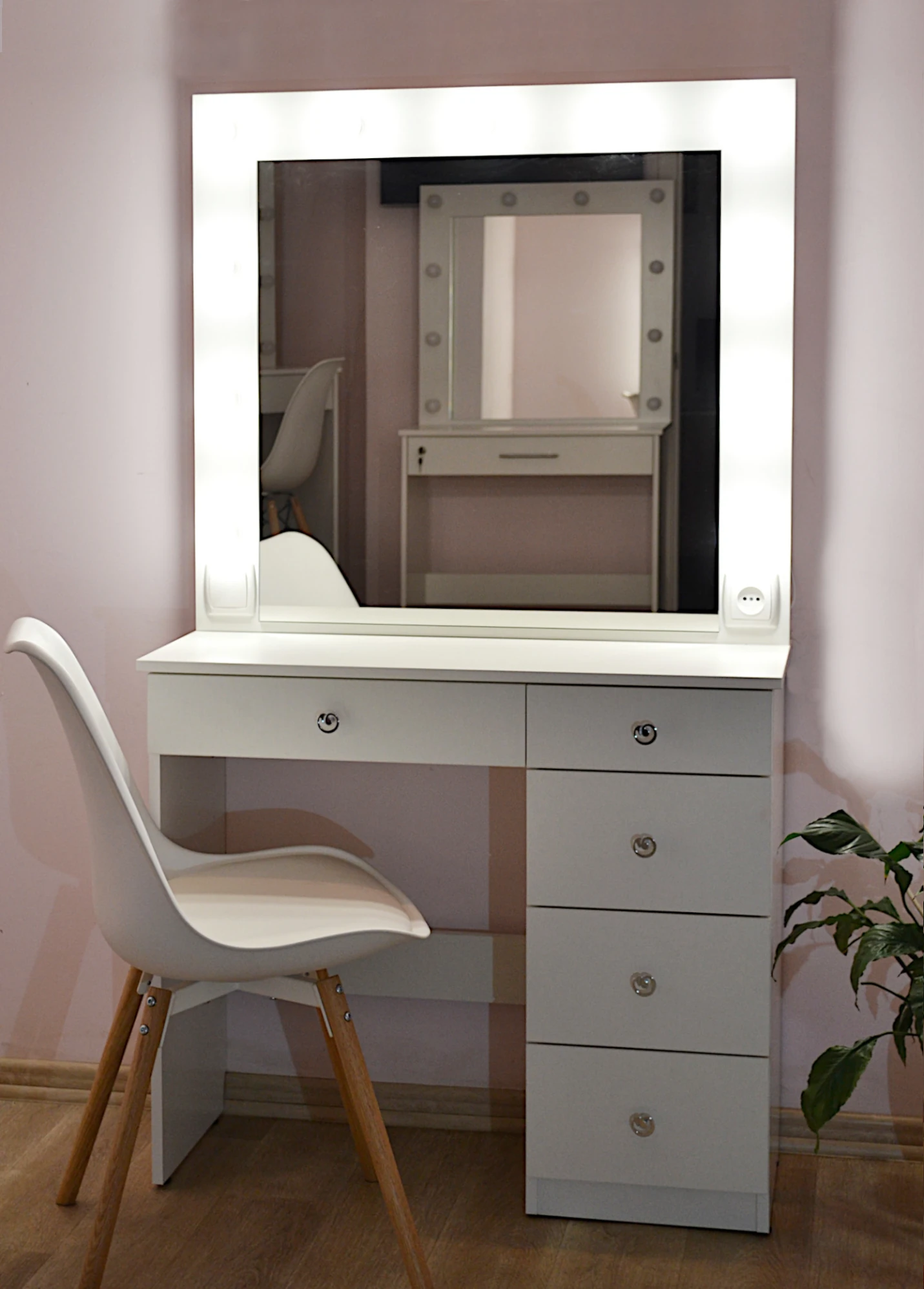 Велике біле дзеркало з туалетним столиком під ним, навколо дзеркала лампочки.